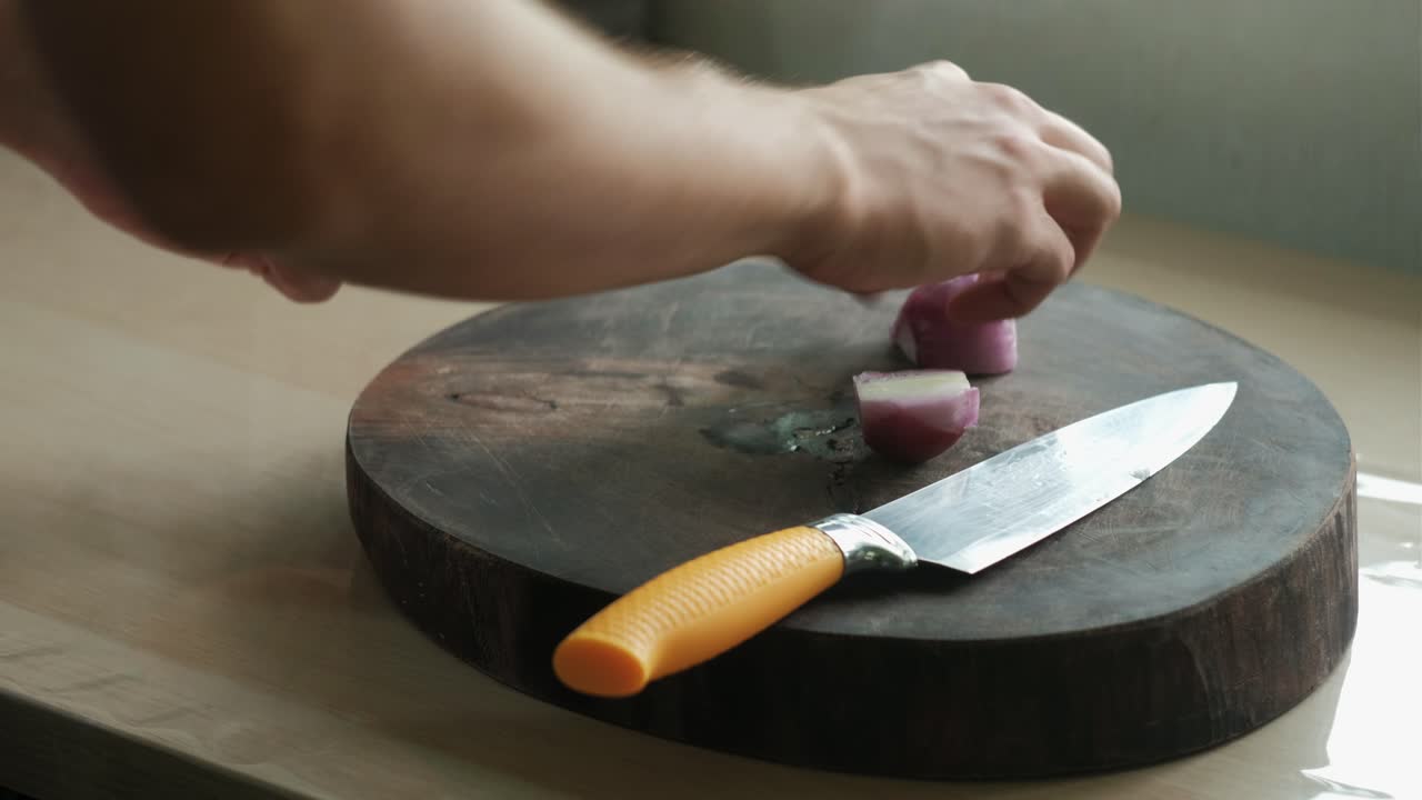 Peeling Red Onion On Wooden Chopping Board In Kitchen. closeup shot