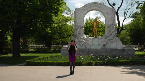 Asiatische-Frau,-Die-Vor-Der-Strauss-Statue-Steht-Und-Mit-Ihren-Haaren-Spielt---Zeitlupe