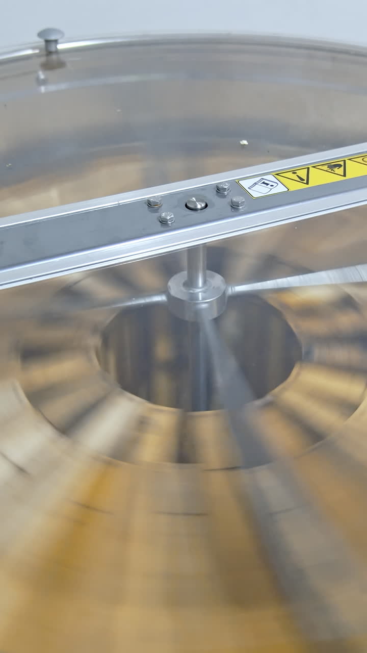 Spinning of frames with honey in a honey extractor. Process of pumping natural honey in modern centrifuge machine. Getting honey from honeycombs in special device. Close-up. Vertical video