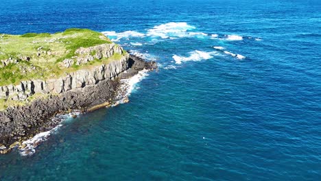 waves crash against hexagonal rock formations