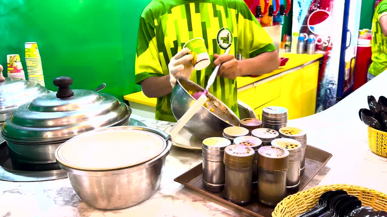 A street vendor preparing boiled corn mixed with various spices and flavors in a colorful stall