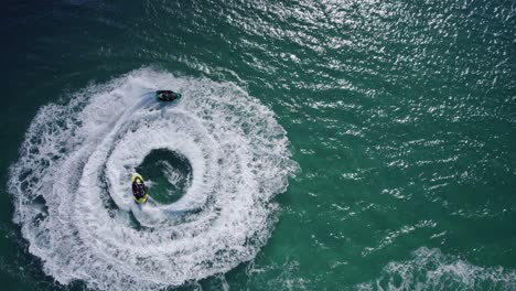 jetskiing - jetskiers circling in the water leaving wake in the blue sea in nsw, australia