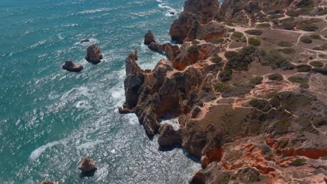 Scenic-lookout-point-where-strong-ocean-waves-meet-land,-winding-sandy-trails