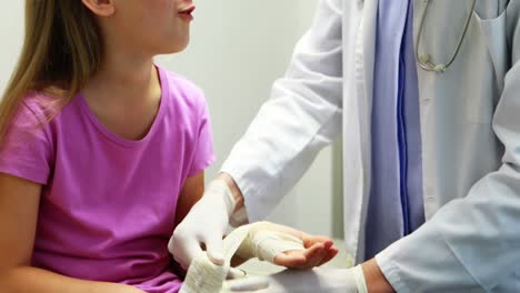 médico de sexo femenino poniendo vendaje en la mano herida de la niña
