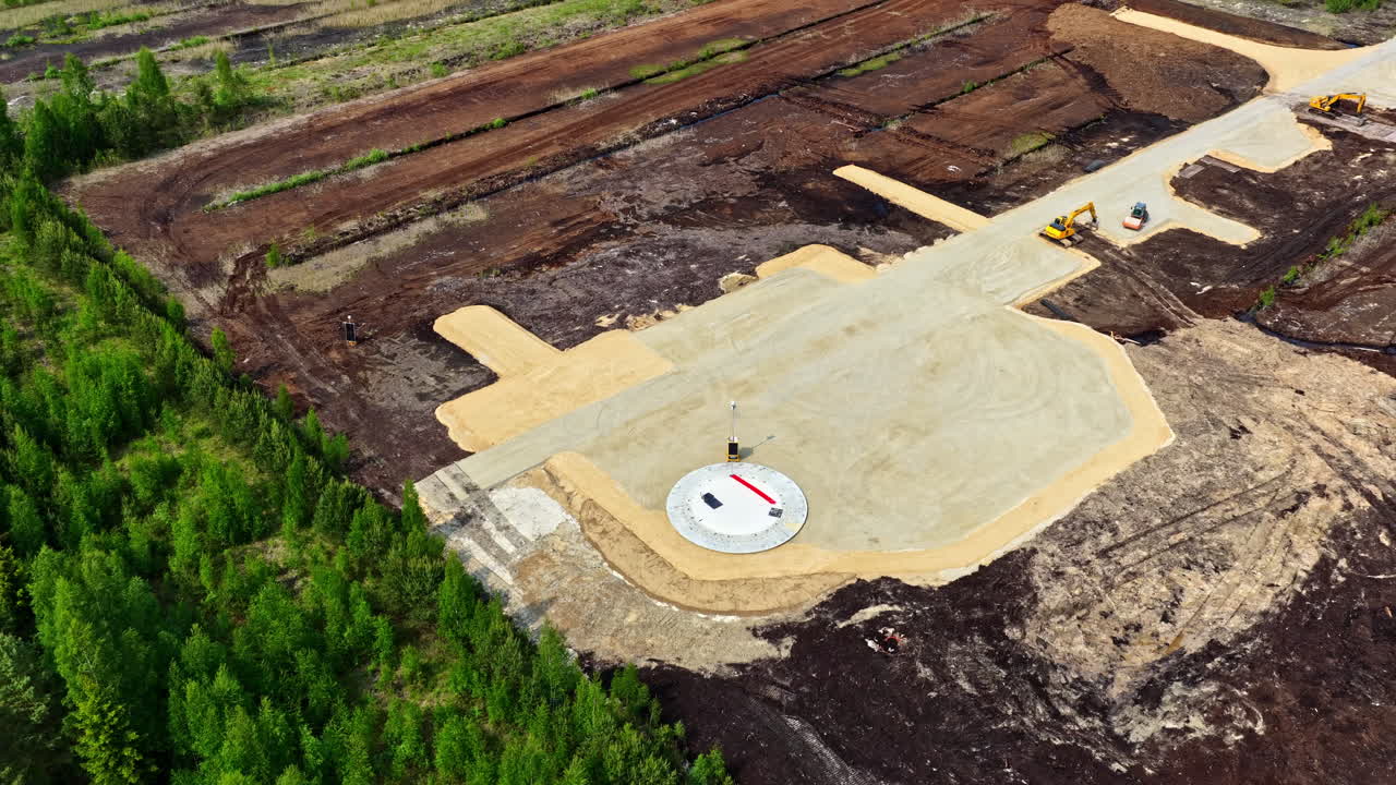 Wind turbine foundation construction site surrounded by peat fields and forest landscape