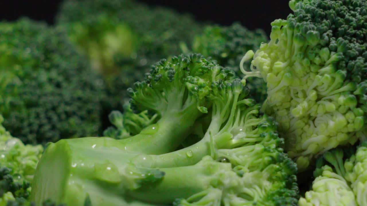 Fresh broccoli pieces on black background, Extreme Closeup Pan Right