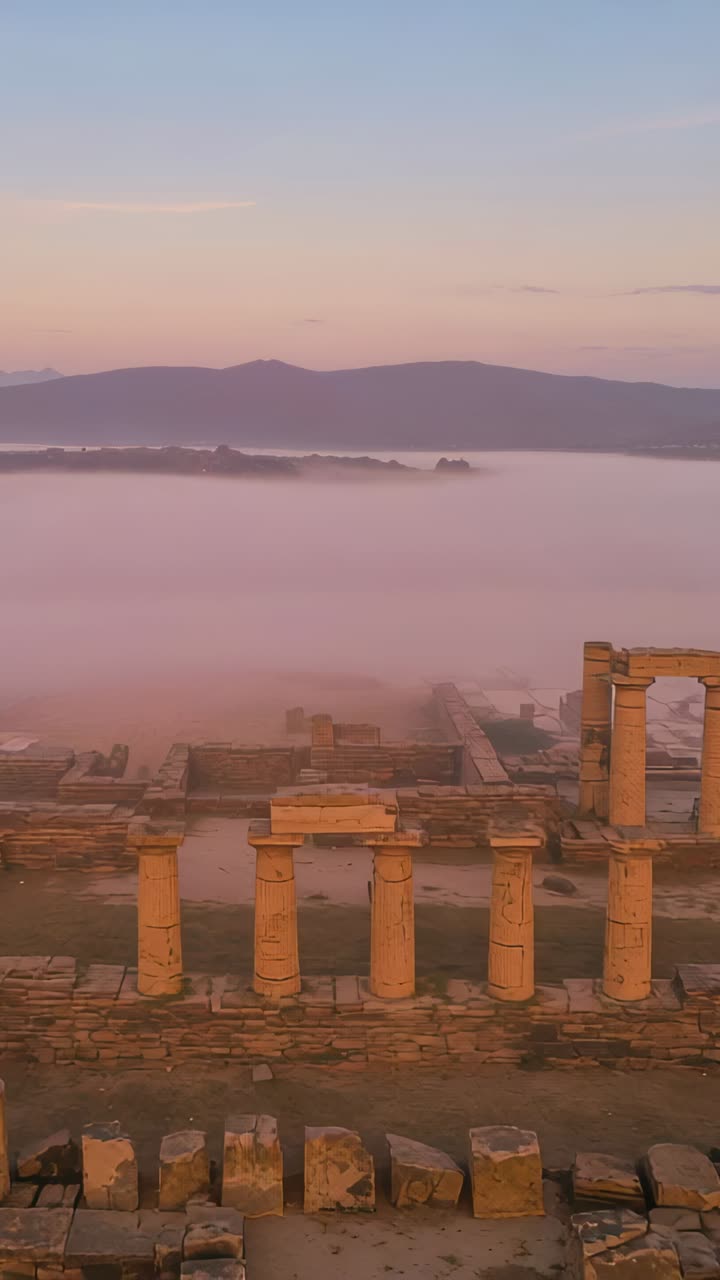 Vertical video: Sunrise light revealing stone columns on ancient terrace while fog shifting