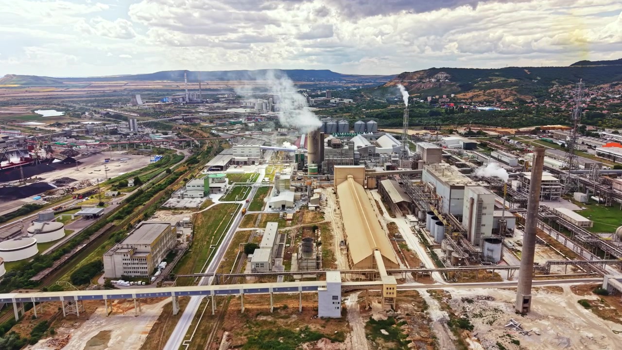 Vista aérea de uma grande área industrial com fábricas, chaminés e maquinário localizado em um ambiente rural durante o dia