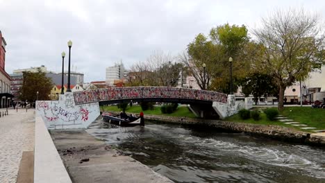 molicero boat navigating under a colorful bridge through aveiro canal, portugal