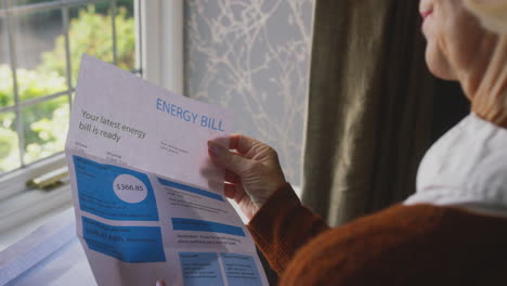 worried senior woman with uk energy bill concerned about cost of living energy crisis