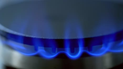 gas is switching on automatically. blue flame appearing on a gas stove on dark background. close-up.