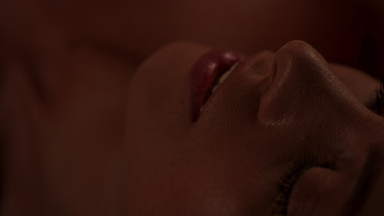 Beautiful macro of an attractive woman's lips and face in a dark room in slow motion