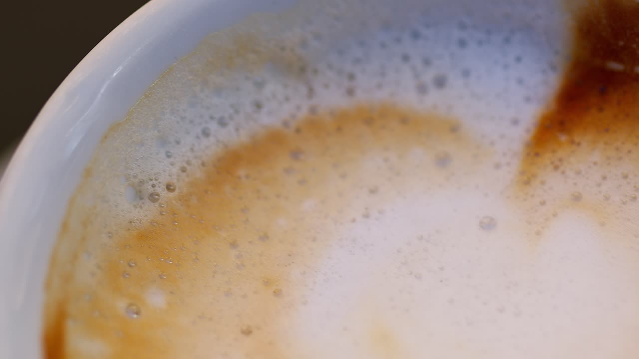 Macro shot of a cappuccino, panning left, showing its texture and bubbles in Italy