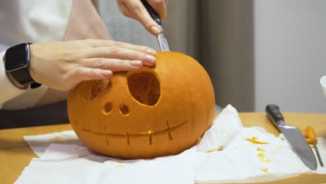 primer plano deslizante de una mujer joven tallando calabaza naranja en casa para la decoración de halloween