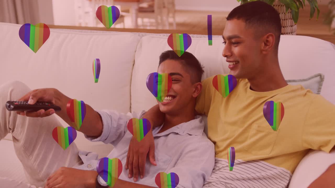 Animation of rainbow hearts over male couple in love watching television