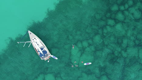 Menschen-Aus-Der-Luft,-Die-Im-Klaren-Wasser-In-Der-Nähe-Des-Segelboots-Schwimmen