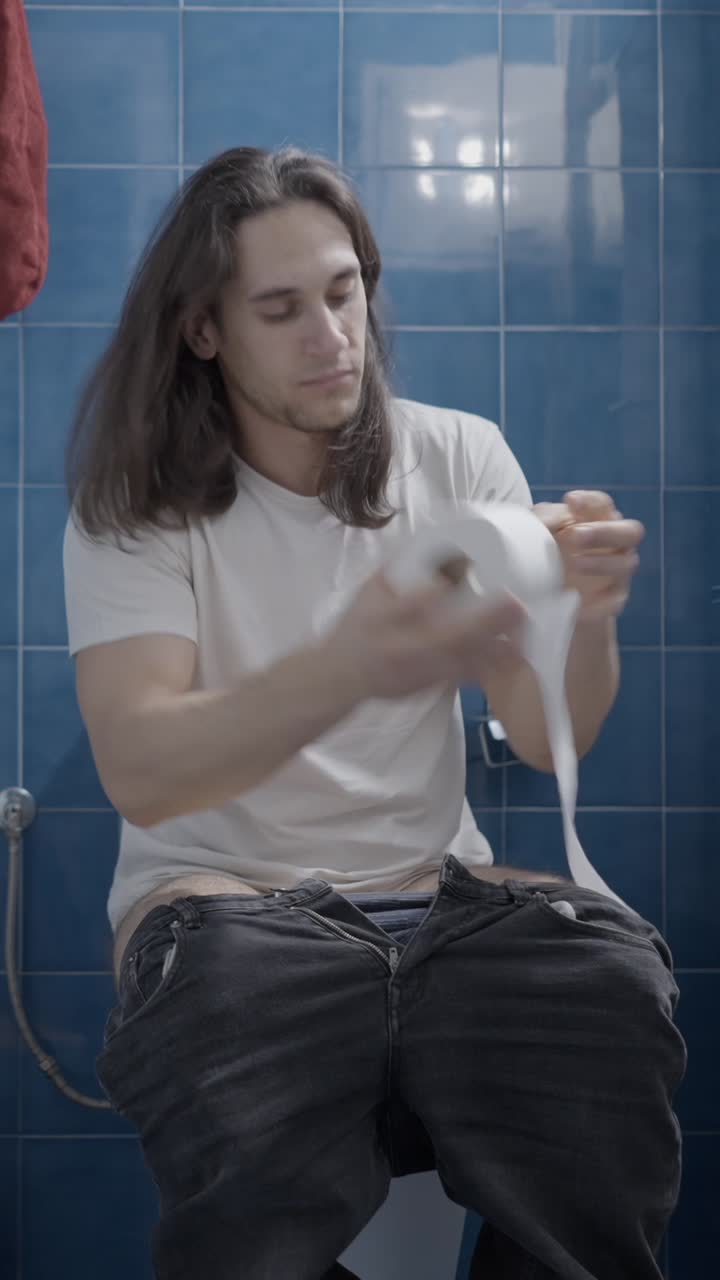 Man Using Toilet Paper in a Bathroom