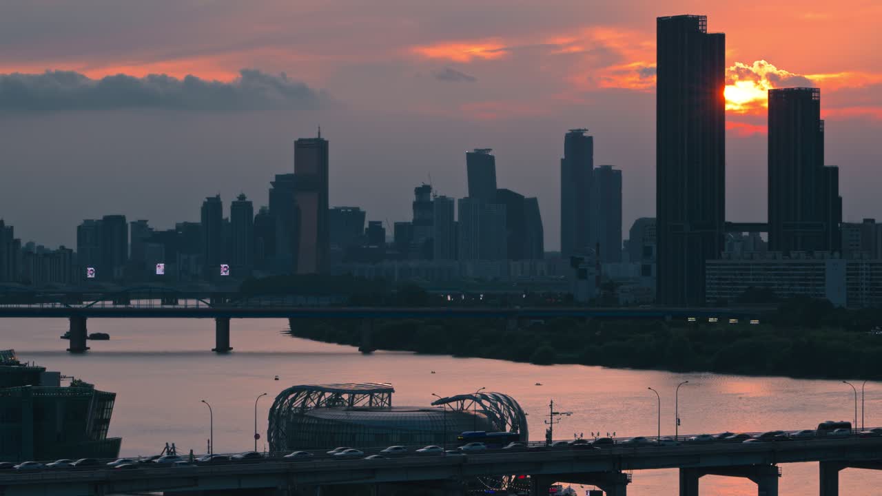Aerial cityscape of Banpo Bridge with vehicle silhouettes set against dramatic sunset behind Raemian Caelitus Tower 101 and the modern Seoul skyline