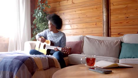 Glückliche-Afroamerikanische-Frau,-Die-Im-Wohnzimmer-Gitarre-Spielt,-In-Zeitlupe