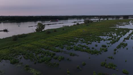 flooded marshland at dusk with patches of green vegetation reflecting on calm water