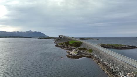 aerial towards famous storseisundet bridge at the atlantic ocean coastal road in norway - sun in sea at left side and ocean horizon on right side