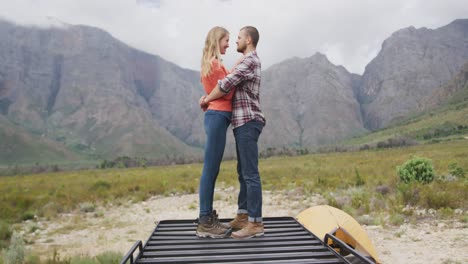 caucasian couple having a good time on a trip to the mountains, embracing and looking at each other