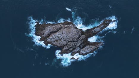 unique aerial view looking down at a rocky outcrop island surrounded by deep blue ocean waters