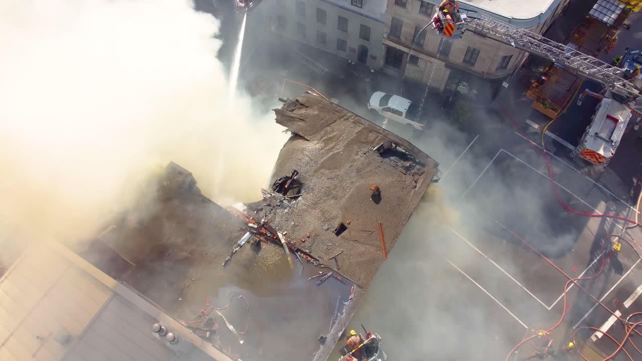 Smoke coming from the destroyed roof of hostel building when firefighters using water jets try to put out the fire aerial shot