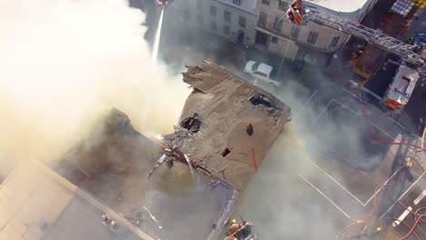 smoke coming from the destroyed roof of hostel building when firefighters using water jets try to put out the fire aerial shot