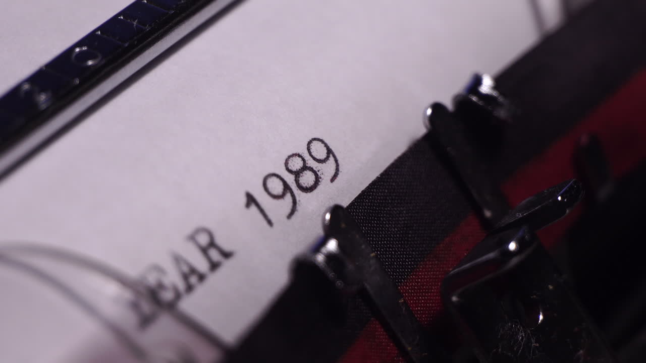 año 1989, escribiendo en papel blanco en una máquina de escribir de época, de cerca