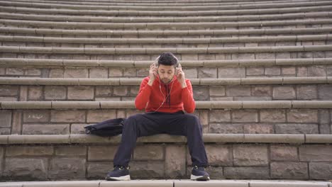 young man in headphones from smartphone listens to music and sings.