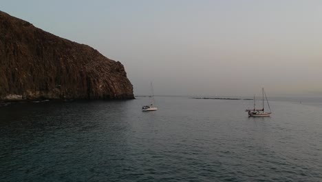 Acantilado-Rocoso-De-La-Costa-De-La-Isla-De-Tenerife-Con-Dos-Pequeños-Botes-Y-Pájaros-Volando