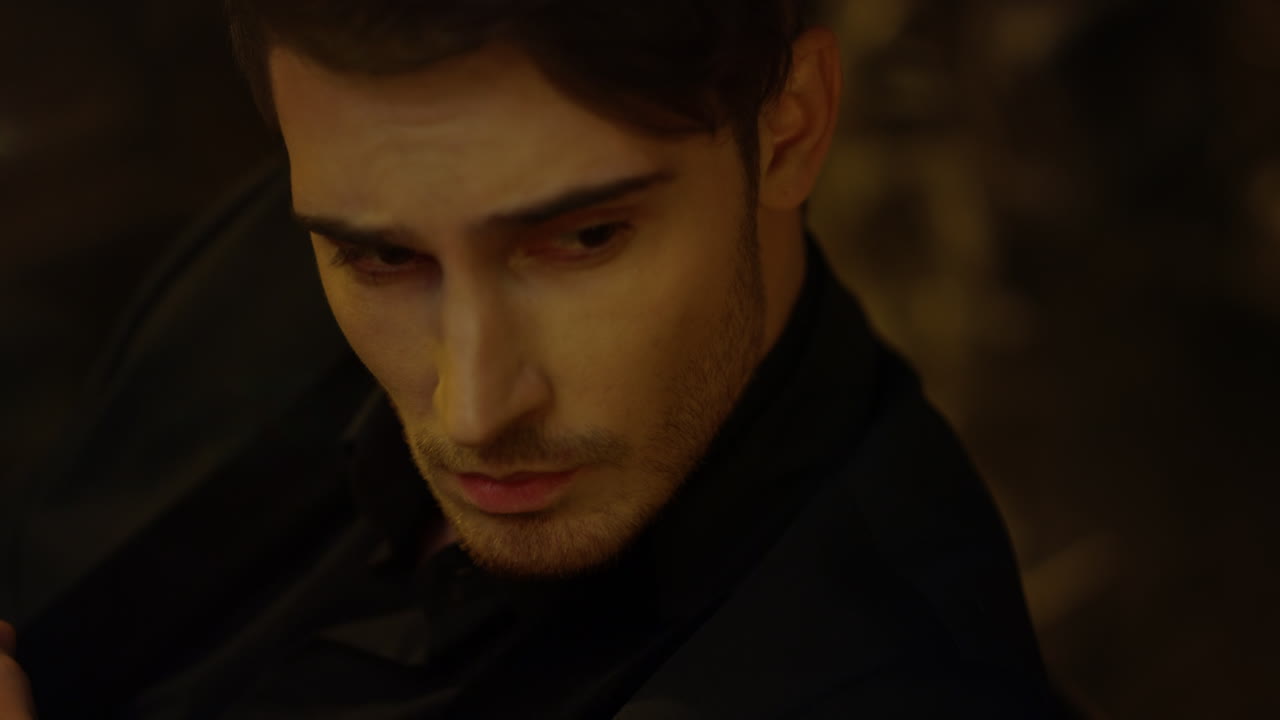 어두운 배경에서 멀리 보이는 예쁜 남자. 무언가를 고려하는 세련된 남자.