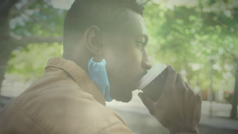 animation of trees in sun with man wearing face mask drinking coffee sitting in street