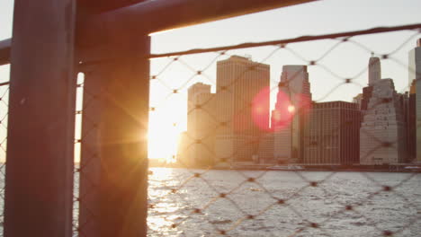 el horizonte de manhattan al atardecer visto a través de una valla de alambre