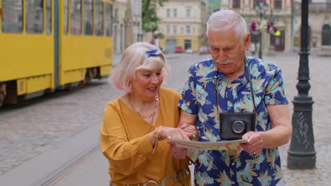 senior stylish tourists man and woman having a walk and look for way using paper map in old city
