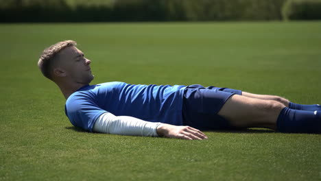 a soccer player resting on a green grass field