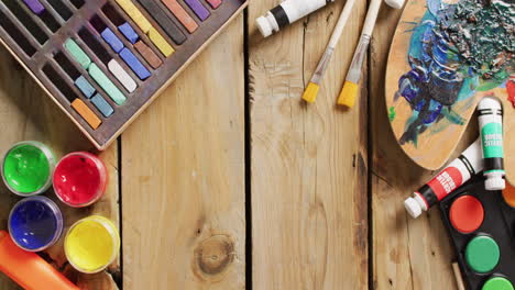 video of paints, paintbrushes, palette and pastels on wooden boards with copy space