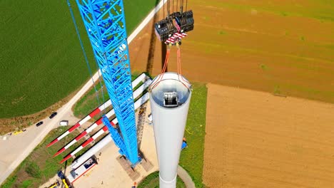 view from above of wind turbine tower erected with lifting crane at farm field in austria