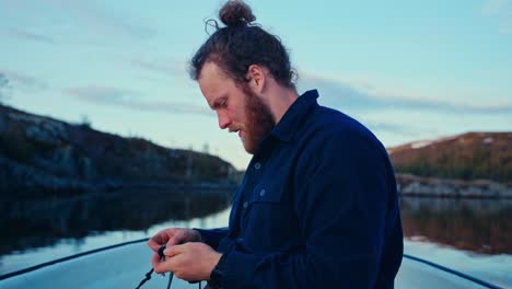 a man prepares a fishing line on a calm evening at lake reinsjøen in åfjord, trøndelag, norway - close up