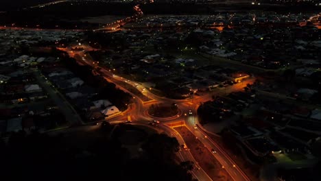 aerial hylerlapse circling around a roundabout on the road at night with traffic in perth western australia