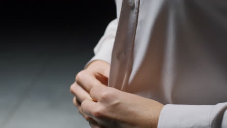 person buttoning a white shirt