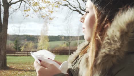 adult girl walking and feeling sick blowing her nose to the tissue in cold sunny autumn day