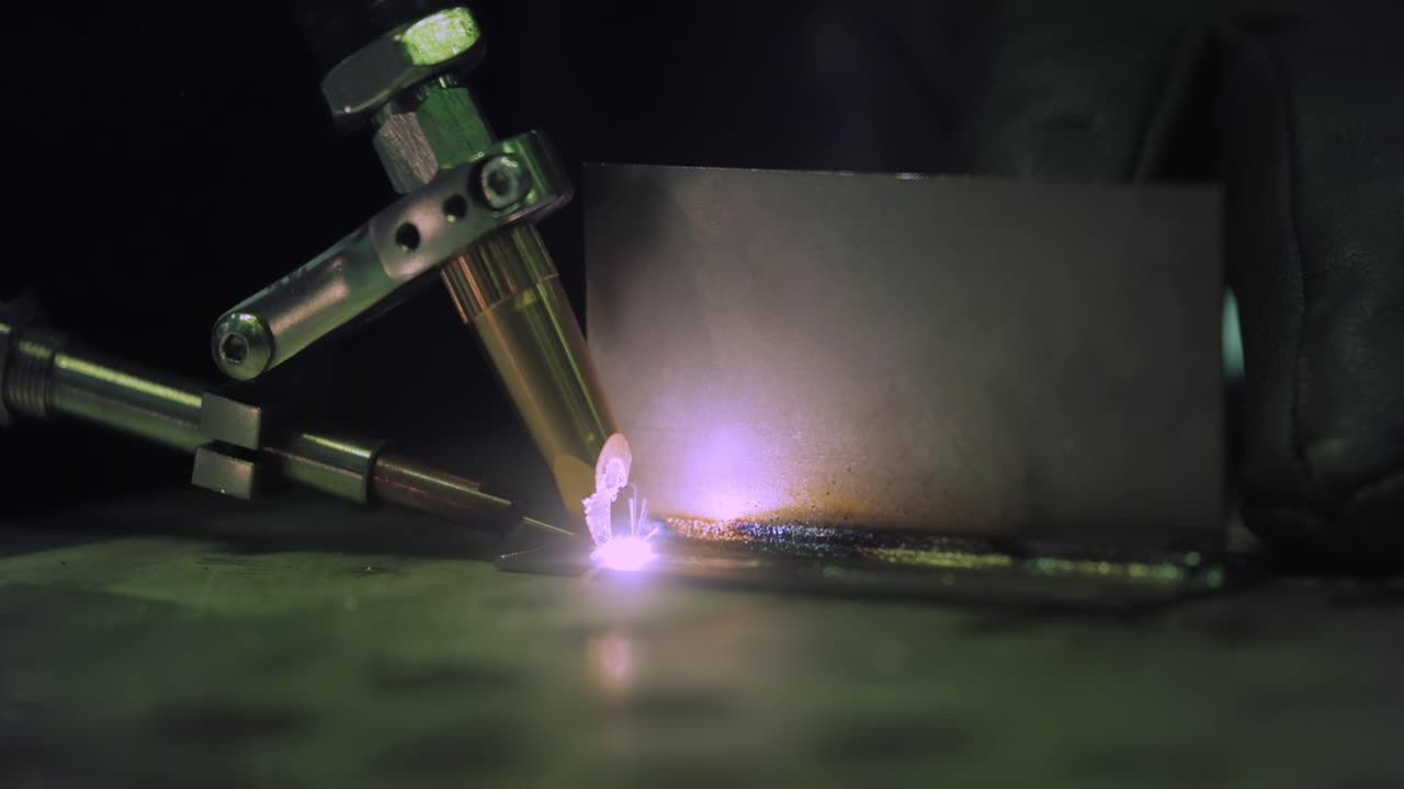 Laser welding machine with hand hold gun. Laser welding is shown in close-up.