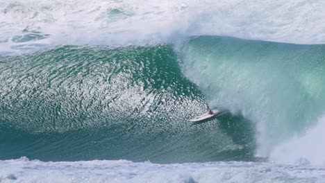 a skilled surfer expertly rides through a massive, curling barrel wave, showcasing balance and precision.