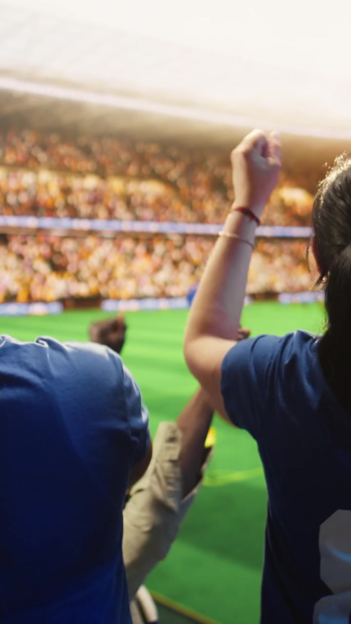 Video verticale. Tifosi di calcio urlano con le braccia alzate in un'arena sportiva