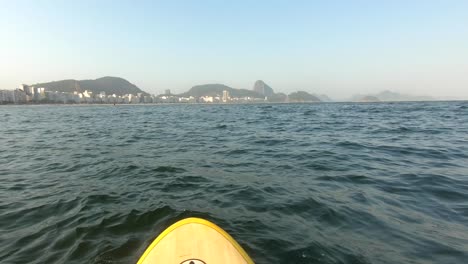 surf de remo en río de janeiro en el mar por la playa con montañas en el fondo
