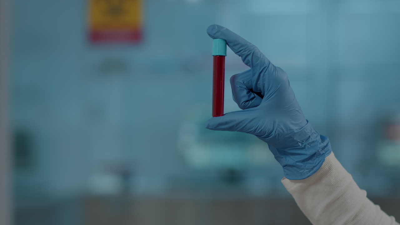 Lab worker holding red substance in test tube for science analysis