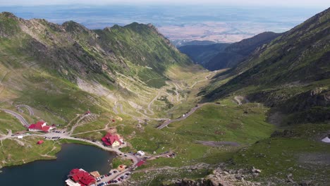 Balea-lake-and-winding-transfagarasan-road-amidst-fagaras-mountains-at-sunrise,-aerial-view