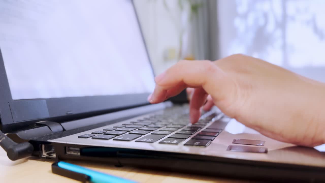 Side view of a woman's hands demonstrating productivity as she types on a laptop.